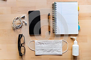 Remote work kit on wooden office desk with hand sanitizer and face mask, a solution against the spread of corona virus for photo