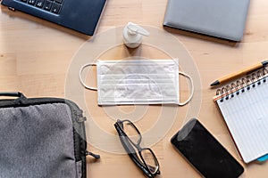 Remote work kit on wooden office desk with hand sanitizer and face mask, a solution against the spread of corona virus for photo