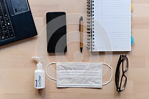 Remote work kit on wooden office desk with hand sanitizer and face mask, a solution against the spread of corona virus for photo