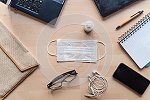 Remote work kit on wooden office desk with hand sanitizer and face mask, a solution against the spread of corona virus for photo