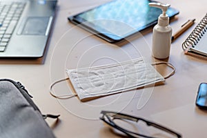 Remote work kit on wooden office desk with hand sanitizer and face mask, a solution against the spread of corona virus for photo