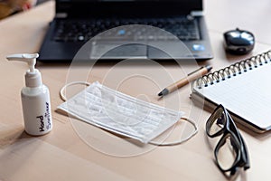 Remote work kit on wooden office desk with hand sanitizer and face mask, a solution against the spread of corona virus for photo