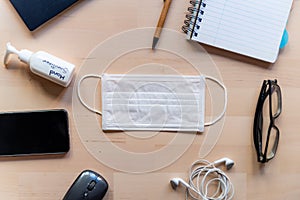 Remote work kit on wooden office desk with hand sanitizer and face mask, a solution against the spread of corona virus for photo