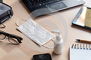 Remote work kit on wooden office desk with hand sanitizer and face mask, a solution against the spread of corona virus for photo