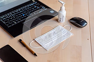 Remote work kit on wooden office desk with hand sanitizer and face mask, a solution against the spread of corona virus for photo