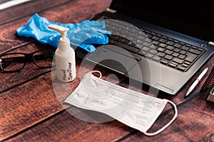 Remote work kit on wooden office desk with hand sanitizer and face mask, a solution against the spread of corona virus for photo