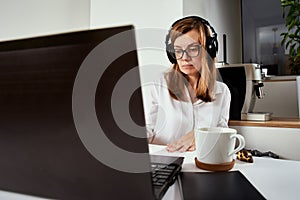 Remote work. Online cources  distance education and e learning concept. Woman in headphones listen audio course at laptop