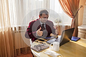 Remote work, Sitting at the kitchen table, a young man in a business suit and shorts, talking on the mobile phone at the same time