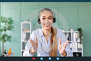 Remote work and technology. Happy woman wearing headphones while having video conference photo