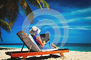 Remote work- young woman with laptop on beach