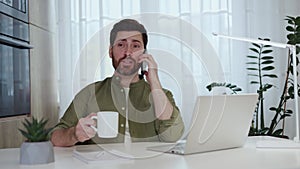 Remote worker communicating via mobile phone on coffee break at desktop