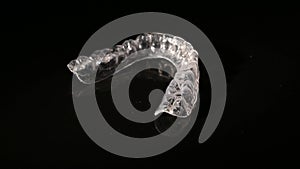 Removable plastic retainers for bite correction revolve against a black background