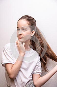 remove birthmarks on face, girl touching thick healthy hair, look away, wearing white T-shirt over white paint wall