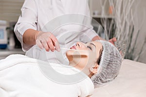 Remove with spatula foam from the face. Young pretty woman receiving treatments in beauty salons. Facial cleansing foam
