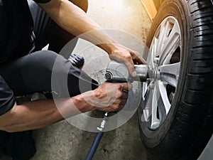 Removing car mechanic to repair the leaky tire car wheels.Mechanic changing a car tire on a vehicle a hoist using an electric dril