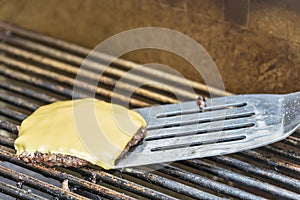 Removing a cheeseburger from a hot grill