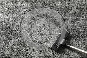 Removing dirt from grey carpet with vacuum cleaner, top view.