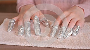 Removing gel Polish from nails. All fingers with foil on both hands. Close-up hand. Front view.