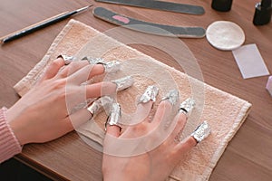 Removing gel Polish from nails. All fingers with foil on both hands. Close-up hand. Front view.