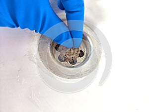 Removing Hair Clog From a Bathroom Sink Drain. Gloved hand extracting hair from a sink
