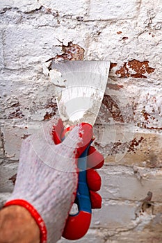 Removing mildew from the brick wall with a metal spatula. Small painting works at home