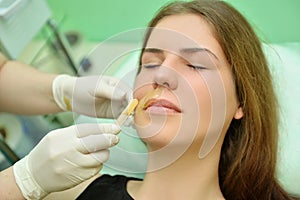 Removing the mustache of a woman with hot wax in a beauty salon
