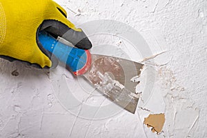 Removing old paint from the wall with a metal spatula. Small painting works at home