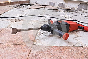 Removing old tiles. Jackhammer - drilling demolition hammer on floor