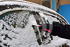 Removing snow from car windshield. Clean car window in winter from snow.