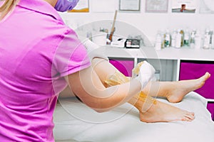 Removing unnecessary hair on the legs. sugaring in a beauty salon. Depilatory