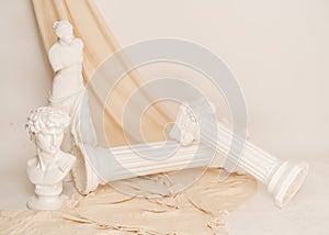 Renaissance epoch gypsum statues arranged with fabric on white background