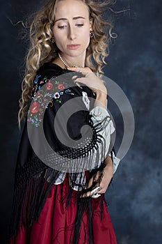 A Renaissance or Gypsy woman wearing a brocade corset and red skirt with an embroidered shawl