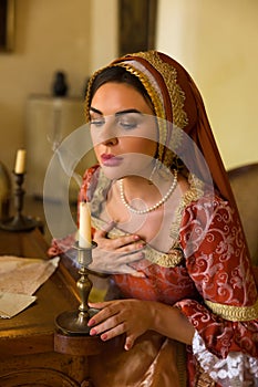 Renaissance woman with French hood blowing candle