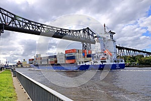 Rendsburg, Germany - August 22 2025: cargo ship pass beneath the Rendsburg High Bridge on the Kiel Canal
