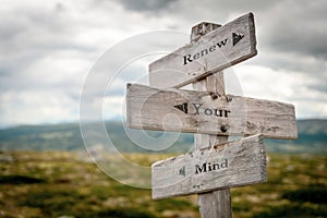 renew your mind text engraved on old wooden signpost outdoors in nature photo