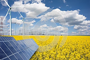 Renewable or green energy concept with wind turbines solar panels and yellow raps field on blue sky with clouds photo