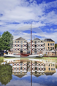 Renovated monumental mansion with white moored boat reflected in canal, Gouda, netherlands