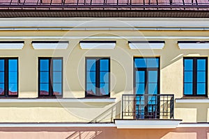 Renovated old building facade with rows of windows and balconyÑŽ closeup view