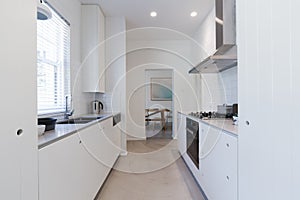 Renovated white galley style kitchen in modern apartment