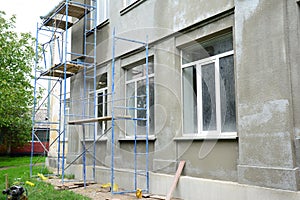 Renovating the facade of a building by applying stucco finish, plastering and finishing the exterior walls using scaffold or