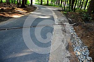Renovation of asphalt road in the mountains. The ditches are filled with stones to slow down the water flowing out of the metal gr