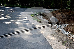 Renovation of asphalt road in the mountains. The ditches are filled with stones to slow down the water flowing out of the metal gr