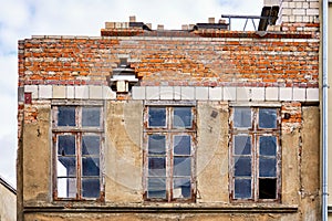 Renovation of the facade of an old house with broken old wooden windows. New and old bricks