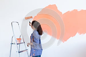 Renovation, redecoration and repair concept - Cheerful woman painting wall in new home. Copy space. photo