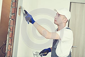 Refurbishment. Worker spackling a wall with putty photo