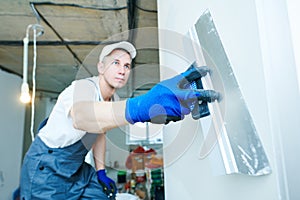Refurbishment. Worker spackling a wall with putty