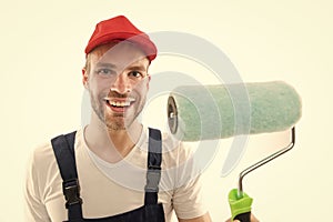 Renovation service. Paint and renovate. Decorator painting wall. Man smiling face in cap hold paint roller close up