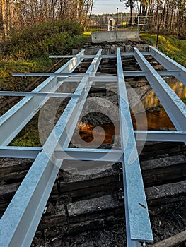 Renovation of a small old bridge. Steel girders painted and in good condition lying on rotten and rotten wooden sleepers