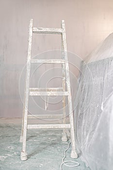 Renovation of a wall in empty room with ladder