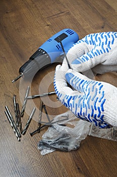 Renovation work indoor.Man holding huge bolt against wooden floor.Screwdriver and drills on the floor.Vertical shot